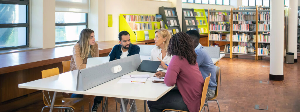 A group of people seated around a table in a classroom.